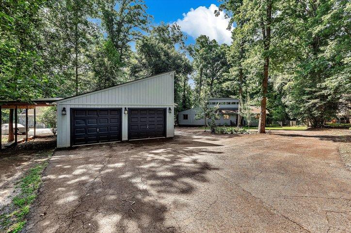 Image 2: A spacious driveway leads to a detached garage.