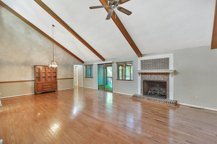 Image 4: A spacious living room features vaulted ceilings w