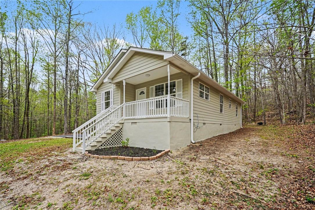Image 1: This charming home features a welcoming porch, nes