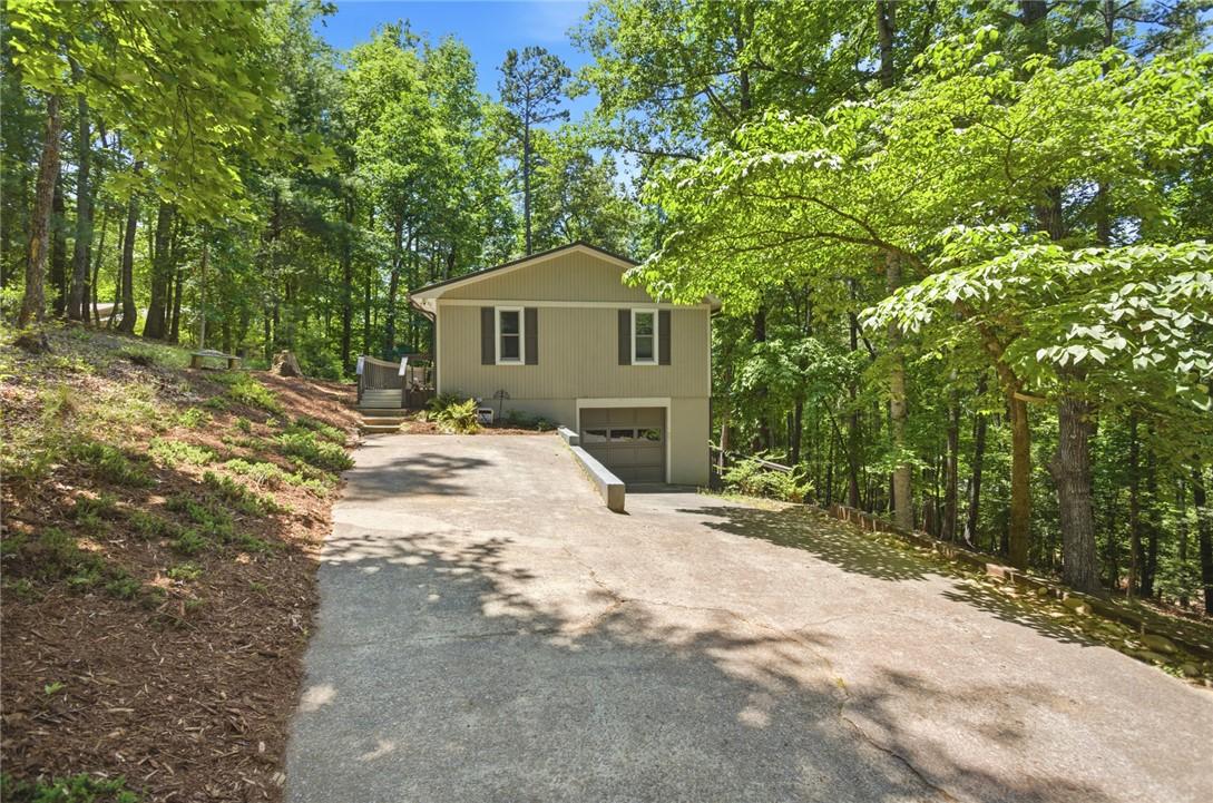 Image 3: A private driveway leads to a tranquil wooded resi