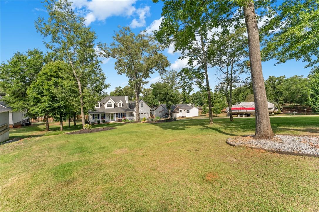 Image 4: A classic white home sits on a verdant lot, framed