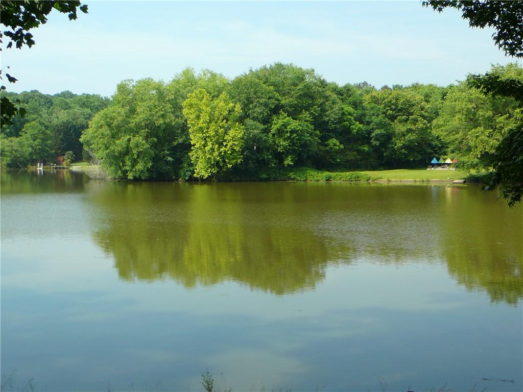 Image 3: Lush, mature trees border a tranquil lake, offerin