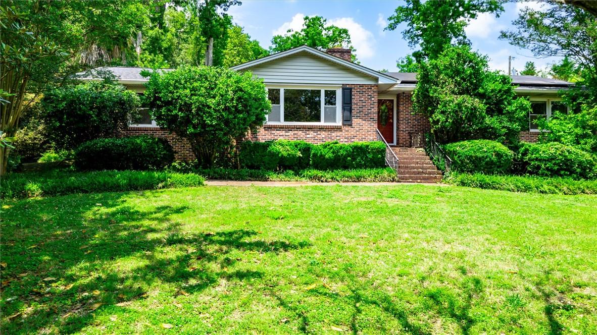 Image 2: Mature landscaping and brick construction define t