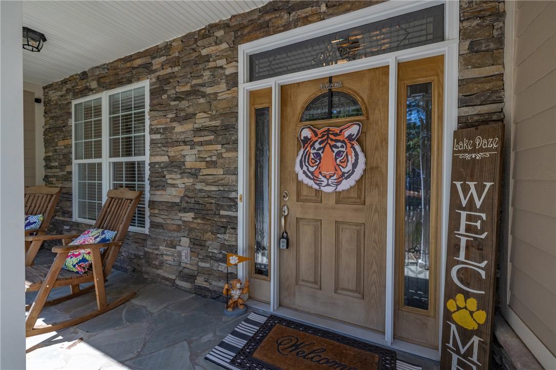 Image 2: A welcoming front porch features rugged stone acce
