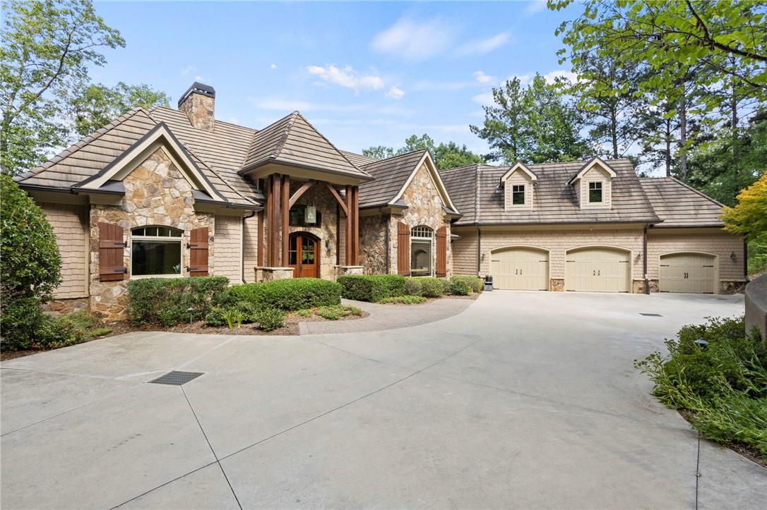 Image 1: A stone and wood home with multiple garage bays is