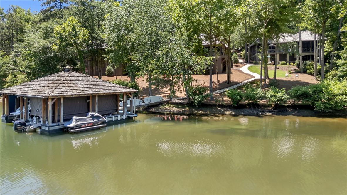 Image 3: Boat dock and covered slips extend from a wooded s