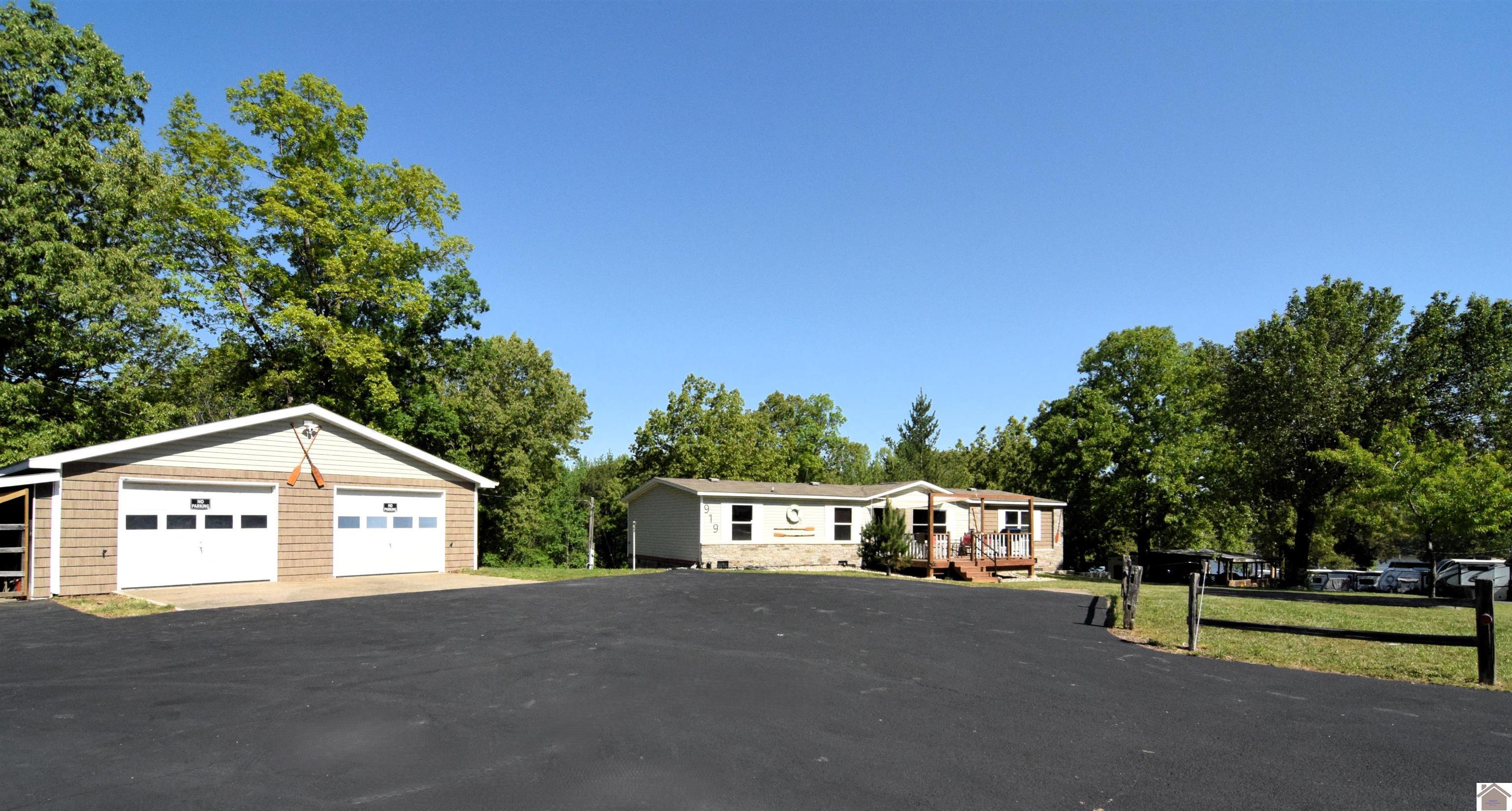Image 1: This property is considered waterfront it connects to TVA. However has Seasonal water view. Lots of parking. There is one camper hook up to the Right of the home. That is being sold as. Camper not included.